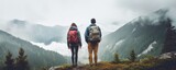 Enjoy nature away from city noise. A hikers couple stand with their backs to the camera against a foggy mountain landscape. Digital detox concept.