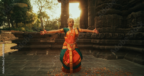 Dynamic Shot of Indian Woman in Traditional Clothes Dancing Bharatanatyam in Colourful Sari While Looking at the Camera. Expressive Young Female Performing Folk Dance Choreography in a Temple © Kitreel