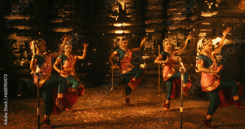 Portrait of Energetic Group of Indian Women Joyfully Dancing Traditional Folk Dance Inside an Empty Historical Temple. Colorful and Captivating South Asian Cultural Celebration photo