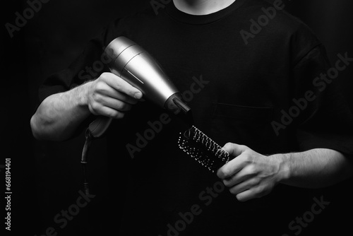 The barber skillfully wields both a hair dryer and a comb, expertly taming and styling the client's hair with precision and finesse. The hands of the hairstylist, set against a black background