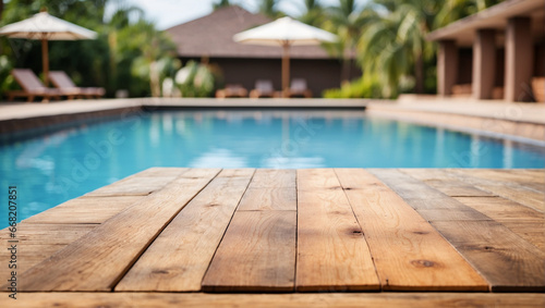 Empty wooden table in front with blurred background of swimming pool © adynue