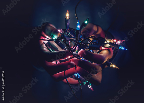 Close-up of hands cupped holding illuminated multi coloured Christmas string lights
