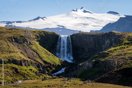 Scenic view of Svodufoss waterfall and Snaefellsjokull glacier in background, Iceland photo