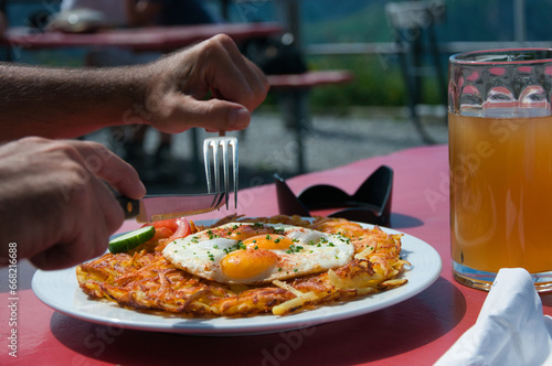 Close-up of a man eating a rosti and fried egg meal with a glass of beer