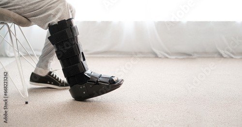 Konstfotografi Injury man with black walker splint on leg sitting on the chair