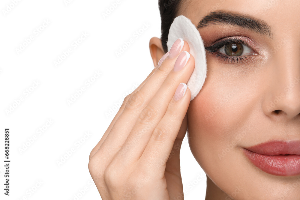 Beautiful woman removing makeup with cotton pad on white background, closeup