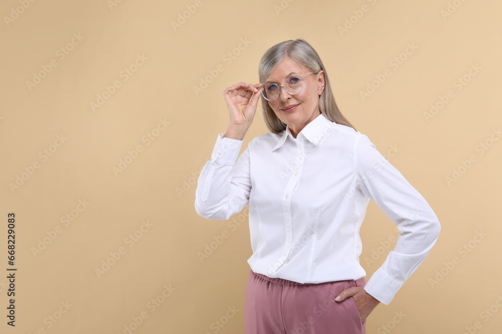 Portrait of beautiful senior woman in glasses on beige background. Space for text Portrait of beautiful senior woman in glasses on beige background. Space for text