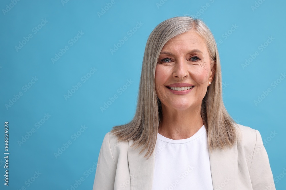 Portrait of beautiful middle aged woman on light blue background, space for text Portrait of beautiful middle aged woman on light blue background, space for text