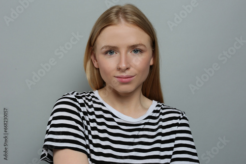 Portrait of beautiful young woman in striped t-shirt on grey background