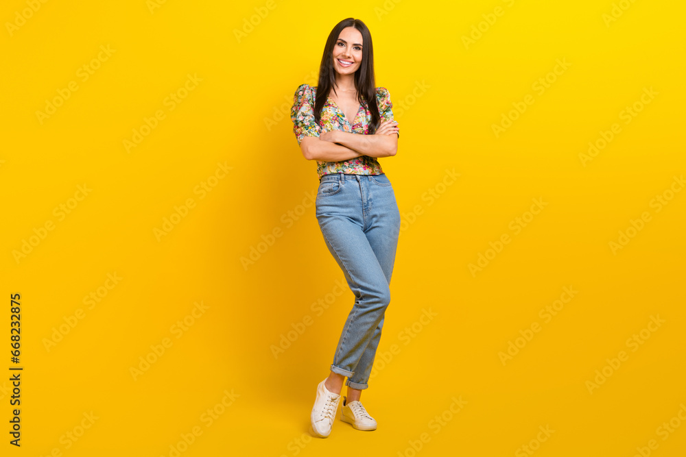 Full length photo of good mood girl with long hairdo dressed flower print blouse standing arms crossed isolated on yellow color background Full length photo of good mood girl with long hairdo dressed flower print blouse standing arms crossed isolated on yellow color background