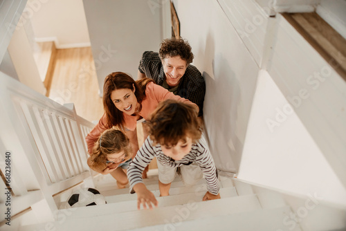 Joyful family playing with a soccer ball on the staircase at home photo