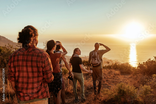 Group of Friends Admiring Sunset After a Coastal Hike photo