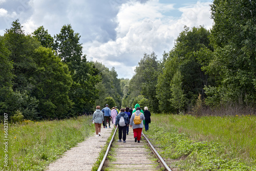 Photography A group of emigrants moves along abandoned railway tracks in the forest