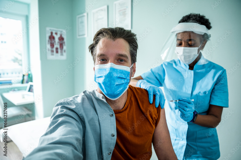 A man takes a selfie as a nurse prepares to give him a vaccine A man takes a selfie as a nurse prepares to give him a vaccine