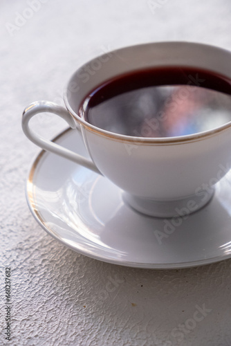 red colored tea in porcelain cup on white background 