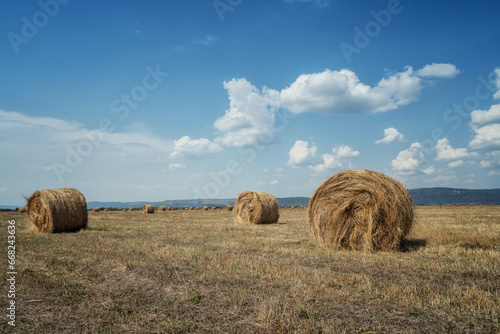 Amazing view with an autumn field full of hay bales and blue sky with fluffy white clouds