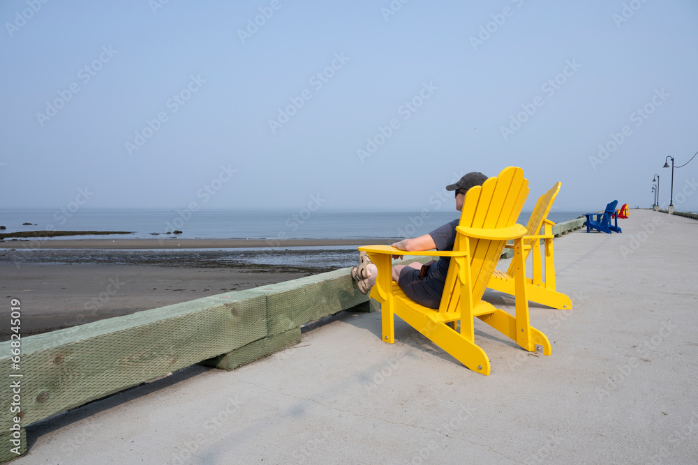 A woman sitting on a yellow chair and looking at the ocean A woman sitting on a yellow chair and looking at the ocean