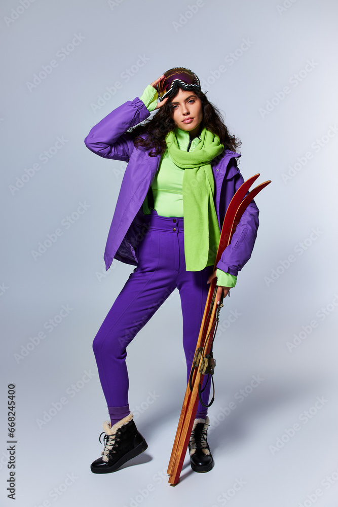 winter sport, brunette woman with curly hair posing in active wear with puffer jacket and skis winter sport, brunette woman with curly hair posing in active wear with puffer jacket and skis