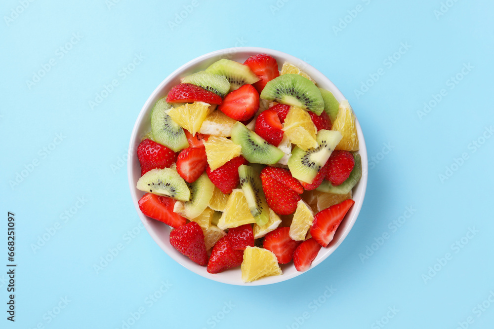 Yummy fruit salad in bowl on light blue background, top view Yummy fruit salad in bowl on light blue background, top view