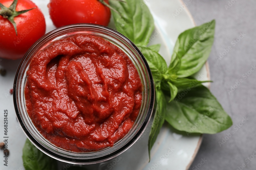 Jar of tasty tomato paste and ingredients on table, flat lay