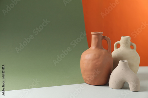 Clay flagons and vase on color background, space for text photo