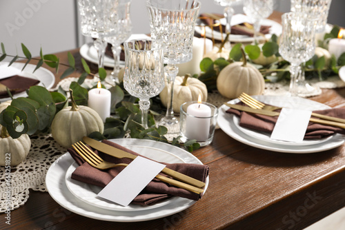 Beautiful autumn table setting. Plates, cutlery, glasses, blank cards and floral decor