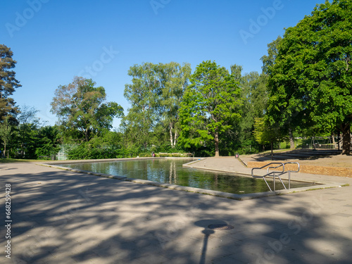 Empty childrens pond in park in summer with blue sky