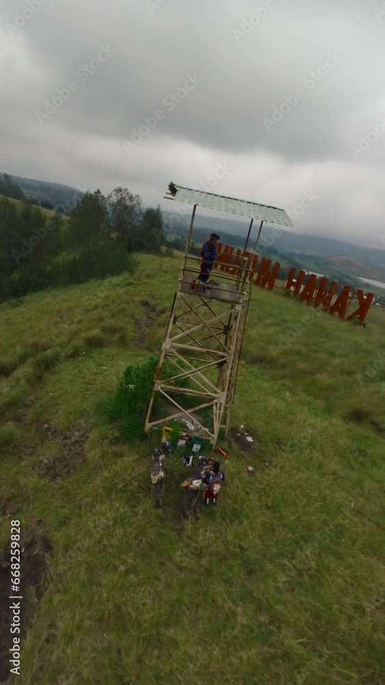 Vertical video. Aerial around fpv drone pilot remote control in goggles mountain hill observation deck wooden tower. Tourist place with big red letters name wild nature tourist tropical country travel Vertical video. Aerial around fpv drone pilot remote control in goggles mountain hill observation deck wooden tower. Tourist place with big red letters name wild nature tourist tropical country travel