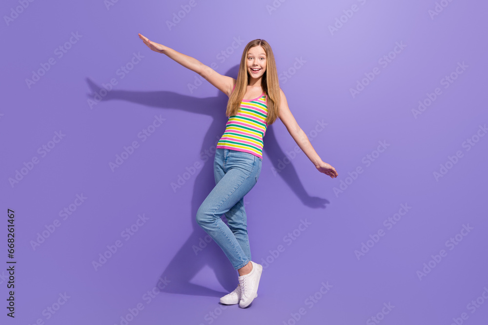Obraz premium Full size photo of pretty teenager blonde girl flying hands wings dressed stylish striped outfit isolated on violet color background