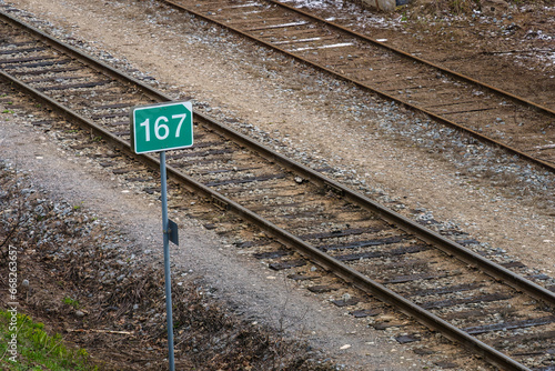 Green sign with number 167 next to railway tracks