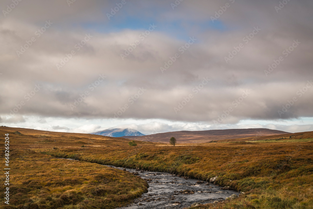 A cloudy autumnal HDR image of Lon Achadh na h-Albhne and a distant Ben Hee at Inchkinloch in Sutherland, Scotland.