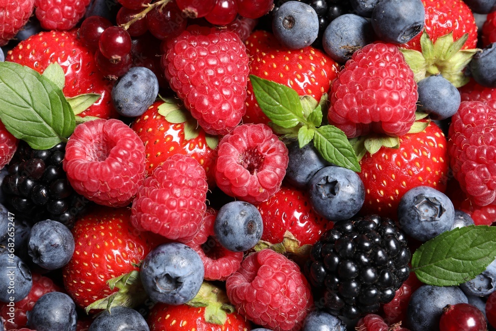 Assortment of fresh ripe berries with green leaves as background, top view Assortment of fresh ripe berries with green leaves as background, top view