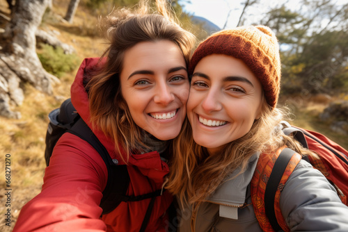 portrait of an affectionate young lesbian couple taking selfies while hiking in In nature