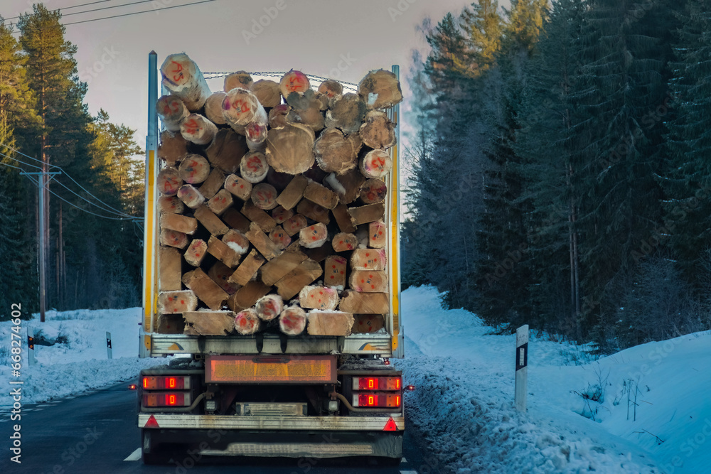 fully loaded timber truck drives through Sweden in winter