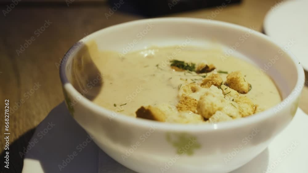 A man eats mushroom soup with croutons and dill with a spoon from a bowl. Vegan cream soup A man eats mushroom soup with croutons and dill with a spoon from a bowl. Vegan cream soup