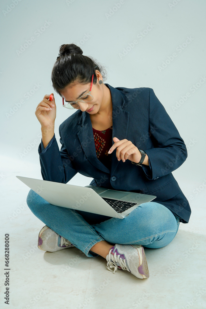 indian girl seated on a white background balances a laptop on her lap indian girl seated on a white background balances a laptop on her lap