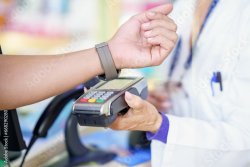 Man paying by smartwatch with dataphone in a pharmacy,
