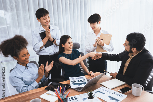 Diverse coworkers celebrate success with handshake and teamwork in corporate workplace. Multicultural team of happy professionals united in solidarity by handshaking in office. Concord