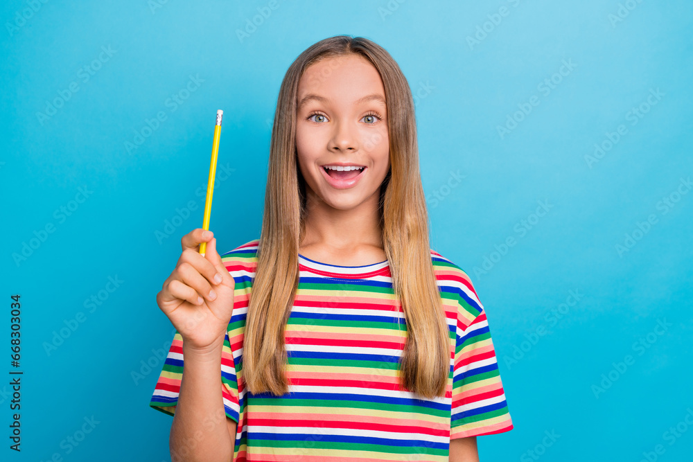 Portrait of clever impressed schoolgirl with long hair wear colorful t-shirt hold pencil have idea isolated on blue color background Portrait of clever impressed schoolgirl with long hair wear colorful t-shirt hold pencil have idea isolated on blue color background