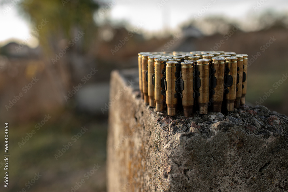 many shell casings from the machine gun belt are placed on a concrete structure. many shell casings from the machine gun belt are placed on a concrete structure.