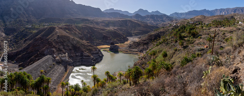 Tirajana Dam also known as Sorrueda Dam, among palm groves of Canarian palm trees. It is part of the World Biosphere Reserve declared by UNESCO. Located in the Tirajana ravine, Gran Canaria, Spain photo