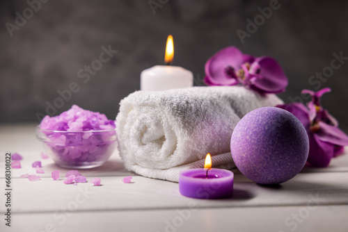 purple bath bomb  sea salt crystals  towel and scented candles on wooden table. body skin care. wellness spa
