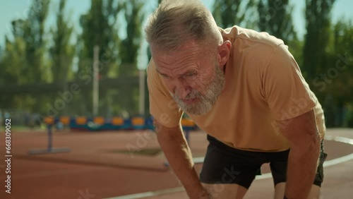 Caucasian exhausted elderly man runner tired jogging sport activity healthy lifestyle stadium outside running exercise fitness training outdoors old senior male have break rest hard breathing dyspnea