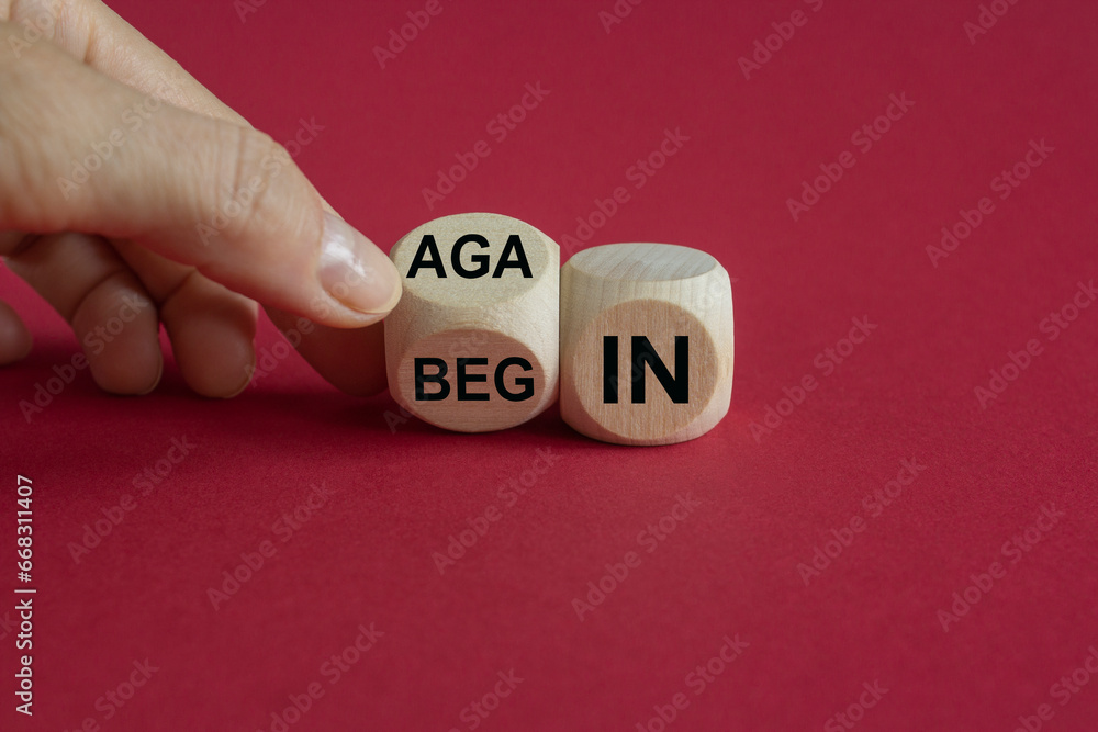 Businessman turns wooden cube and changes the words begin to again. Beautiful red background. Business and begin again concept. Copy space. Businessman turns wooden cube and changes the words begin to again. Beautiful red background. Business and begin again concept. Copy space.