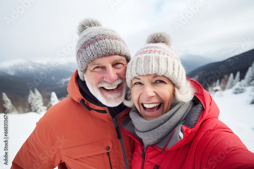 Elderly couple having fun taking and selfie together outdoors in winter in mountains