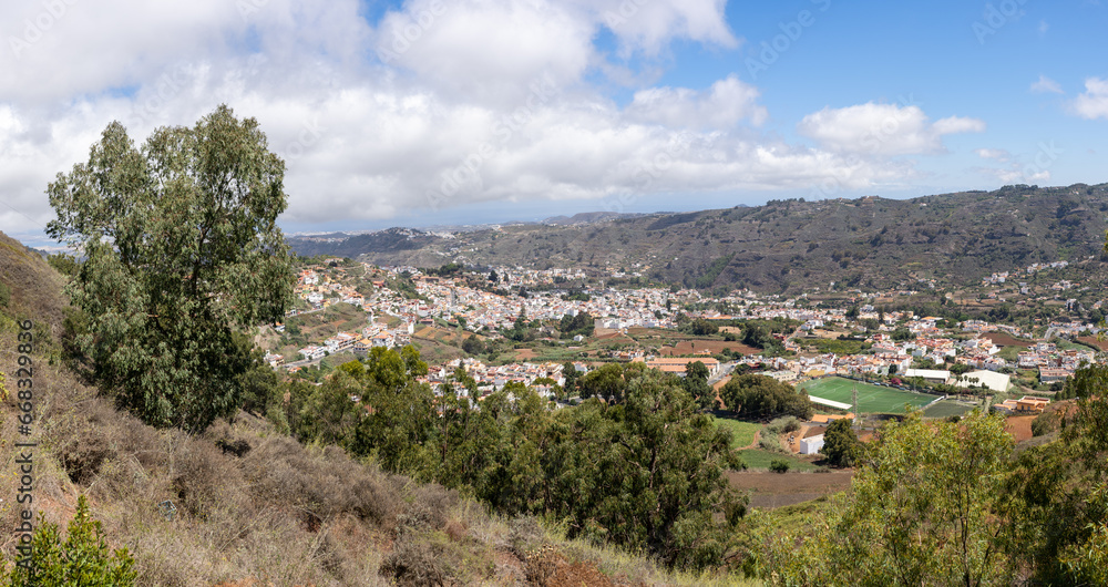 Beautiful panoramic view of Teror between hills covered by green vegetation on sunny day in Gran Canaria island, Spain
