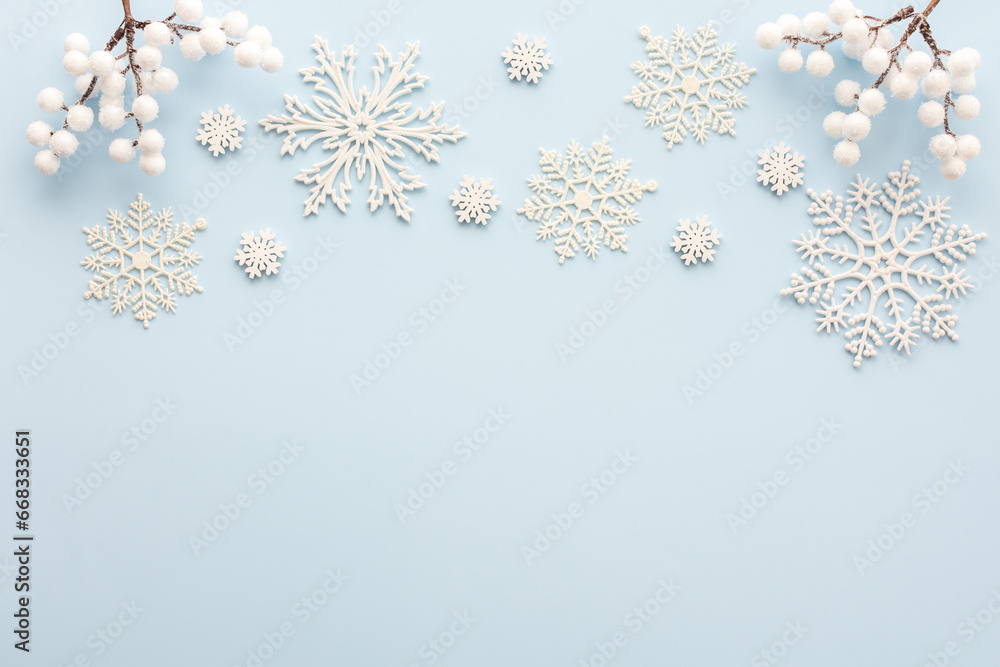 White snowflakes and rowan branches on a blue background, Christmas background, Merry Christmas and Happy New Year concept, top view, copy space