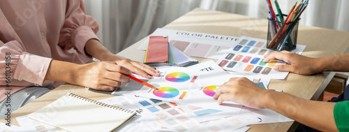 Cropped image of professional interior designers discuss and brainstorm main theme color in project on meeting table with color palette scatter around. Creative interior design concept. Variegated.