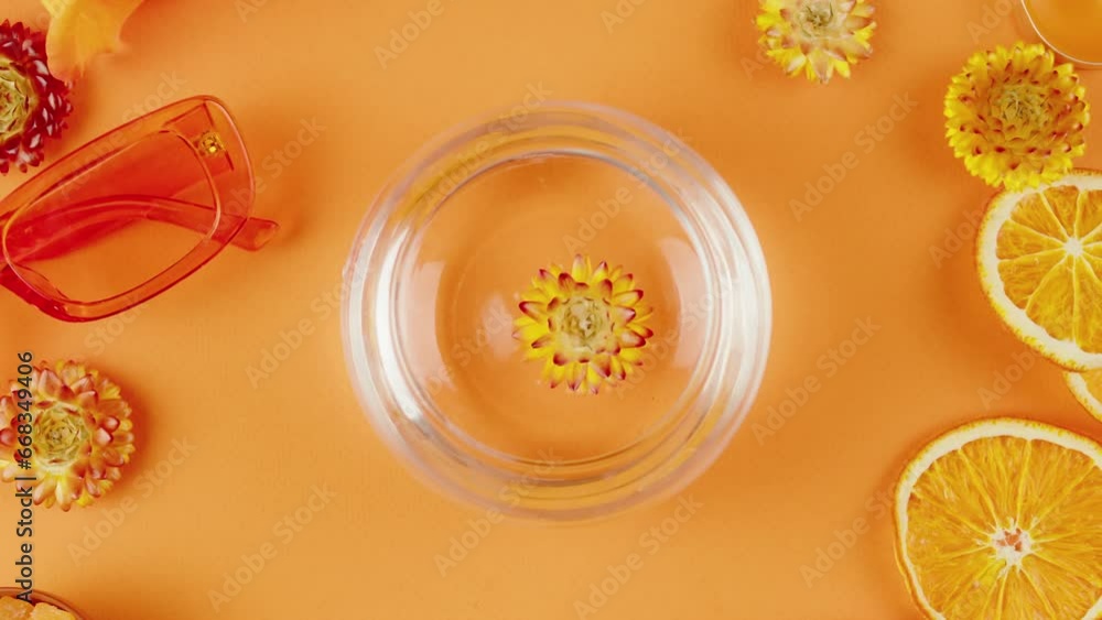 Dried flowers in a jar of water on orange background. Composition of citrus slices, flowers, sunglasses, aroma candles, helichrysum close-up, top view. Summer bright texture studio shot. Dried flowers in a jar of water on orange background. Composition of citrus slices, flowers, sunglasses, aroma candles, helichrysum close-up, top view. Summer bright texture studio shot.