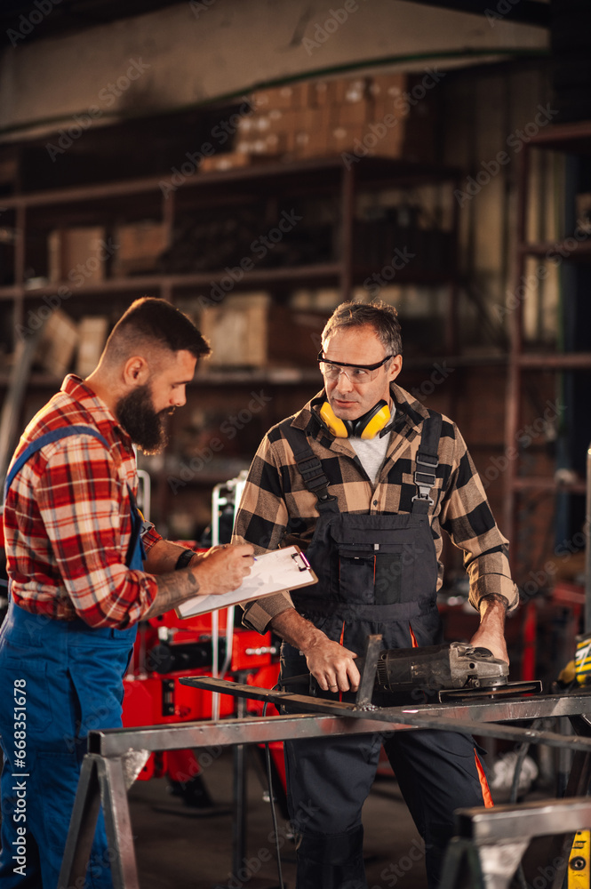 Experienced craftsman sharing new ideas from paper with his colleague.